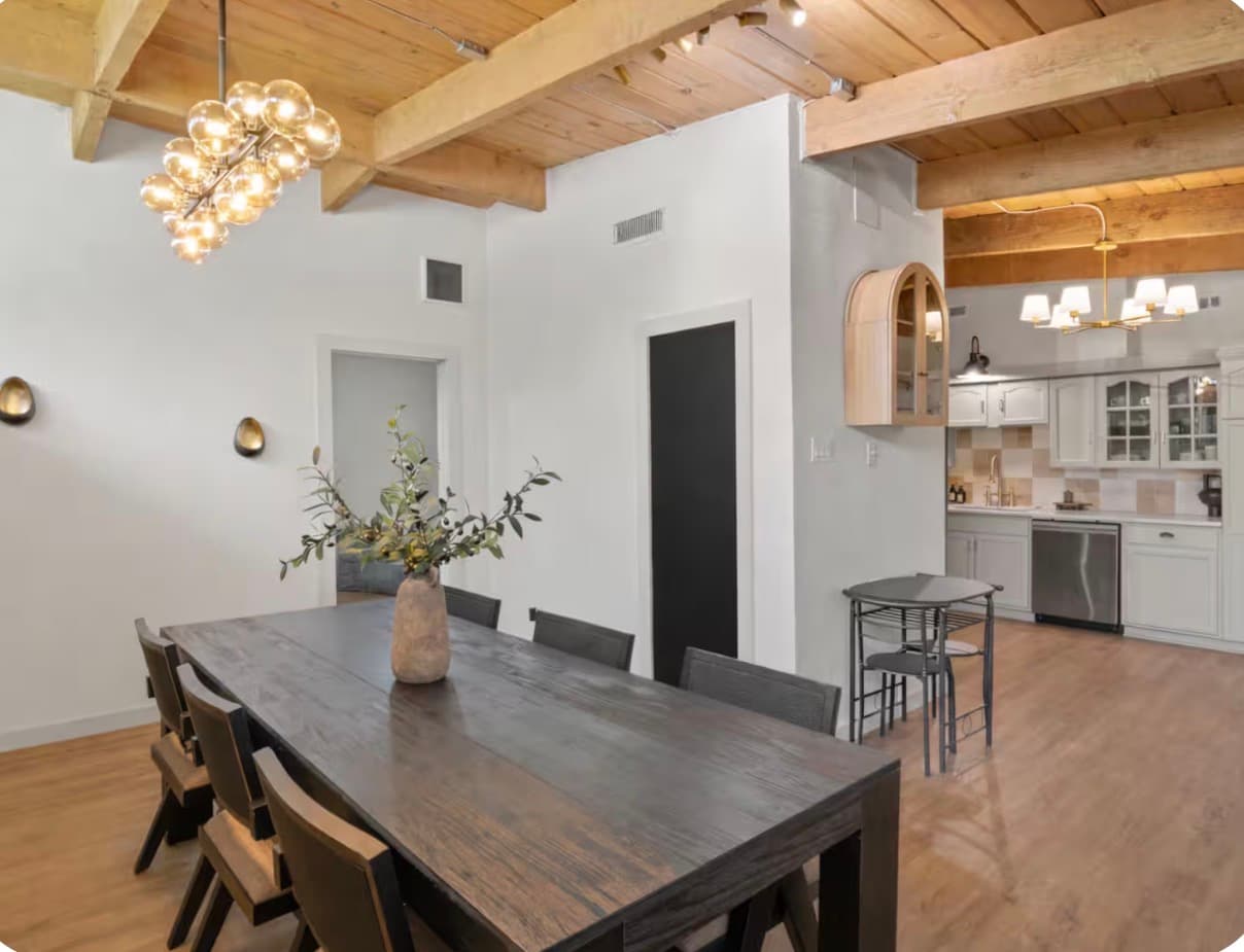Second view across the dining table toward the open kitchen at the Dallas Creative Connect location.
