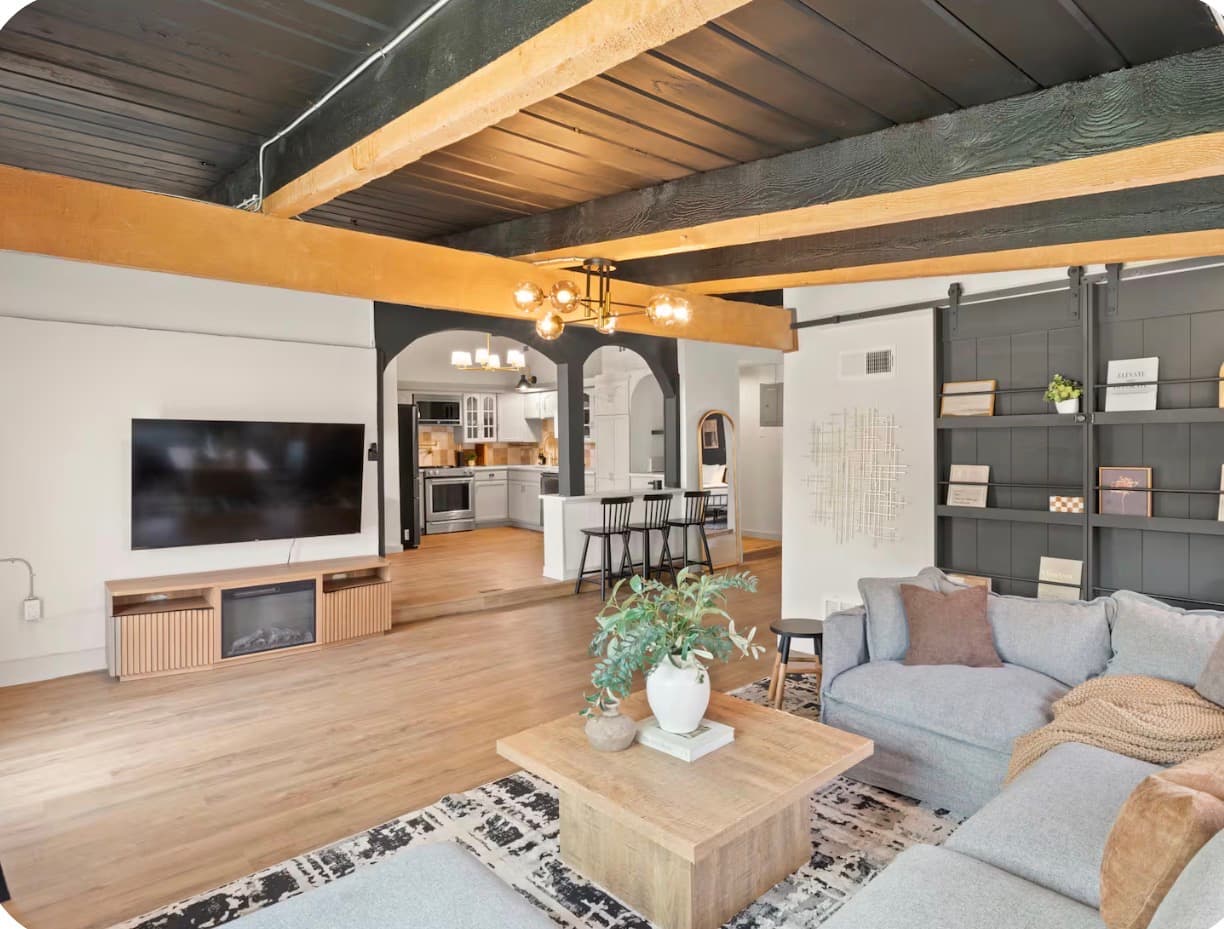 Wide living room with warm wood beams and an open view into the kitchen at the Dallas Creative Connect location.