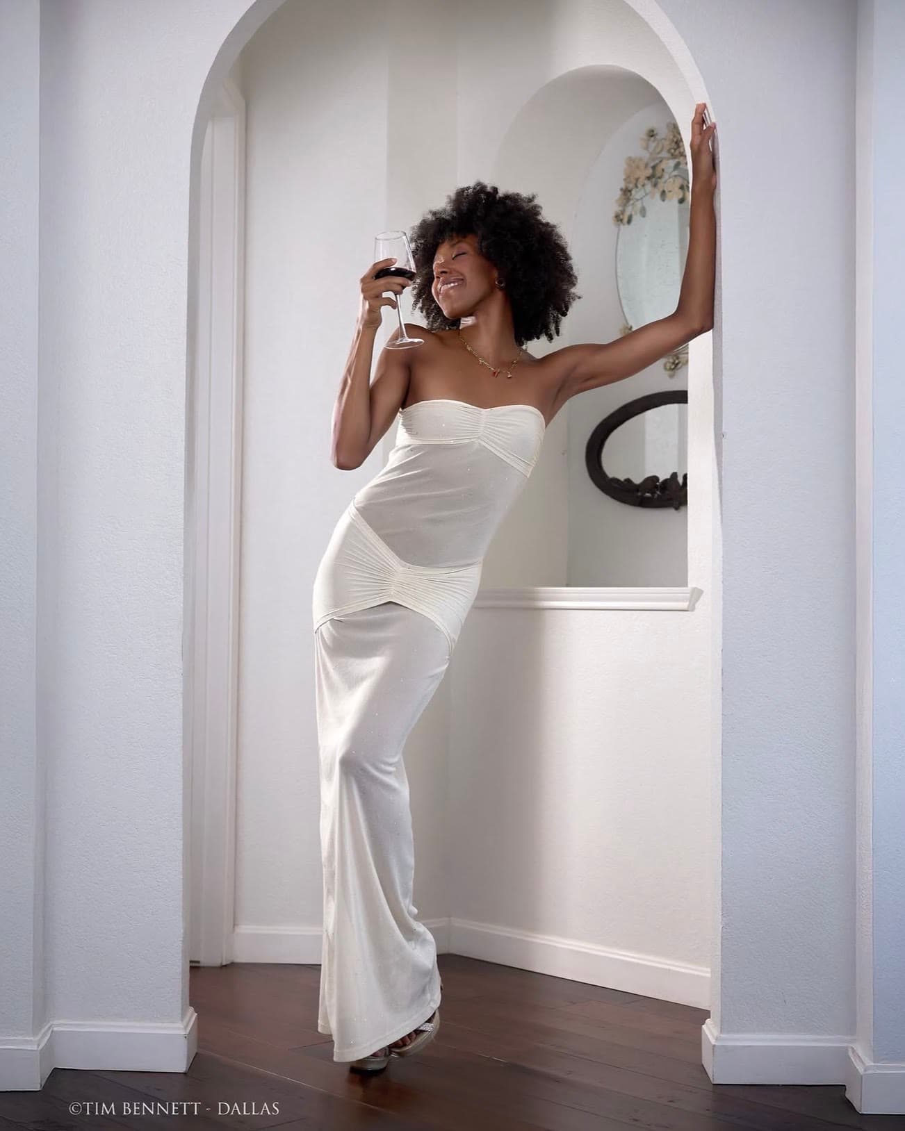 A Creative Connect Rowlett model posing in a white dress beneath an interior archway.